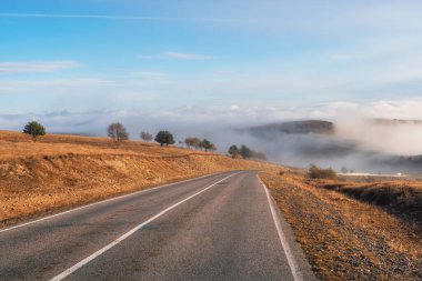 Empty morning highway through the pass in thick fog. Beautiful asphalt freeway, motorway, highway through of caucasian landscape mountains hills at cold weather in mid october.