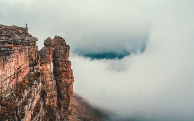Soft focus. Awesome caucasus landscape with silhouette of hiker above white clouds and Rocks of Big Bermamyt - the so-called 