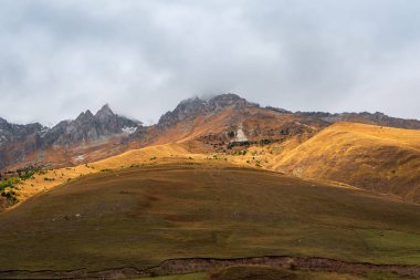 Soft focus. Mountains in a dense fog. Mystical landscape with beautiful caucasian mountains in low clouds. Beautiful rock foggy scenery with sunny slope and dence clouds.