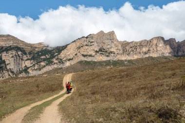 Walking and hiking trails in the mountain range in the sunny day. Family backpacker tourists hiking. Digoria. Caucasus Mountains.