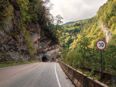 Mountain highway through the pass. Mountain highway, at the entrance to the tunnel cut into the rock. Beautiful street in a rocky tunnel. Digora gorge, North Ossetia-Alania republic.