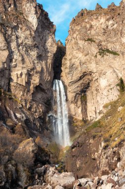 Scenic autumn landscape with vertical big Sultan waterfall at mountain top in sunshine in the Jila-Su tract. Kabardino-Balkaria. Russia, Caucasus. High falling water in Northern Elbrus region.