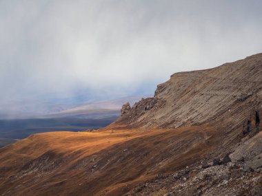Soft focus. Foggy mountain view from cliff at very high altitude. Scenic alpine landscape with beautiful sharp rocks in sunrise. Beautiful scenery on abyss edge with sharp stones. 