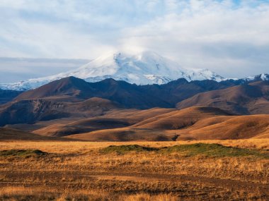 Autumn mountain plateau, picturesque morning sunny view. View of the snowy Elbrus volcano in autumn. Russia, the Caucasus.