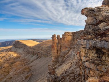 Amazing view of Bermamyt plateau rocks on sunny day. Caucasus Mountains on the edge of a cliff in the distance. Atmospheric landscape with silhouettes of mountains. Karachay-Cherkessia, Russia.