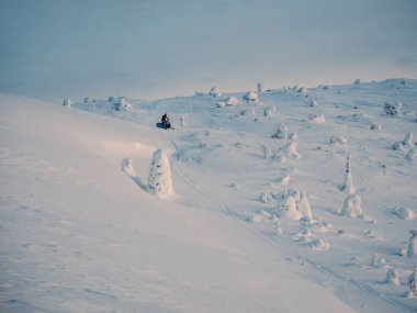 Snowmobile on snowfield. Winter sport. Snowcapped mountains and cloudy weather with blizzard in Khibiny Mountains, Russia.
