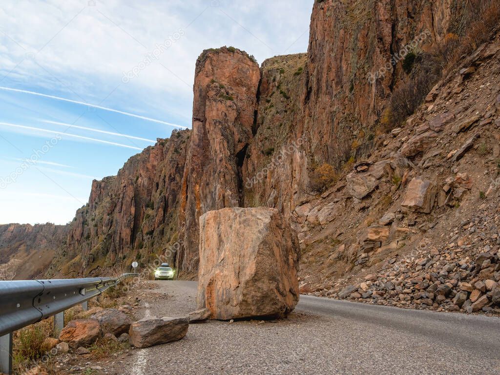Large granite boulder fell on the road. Dangerous mountain road after heavy rains. Dangerous