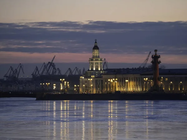 Duwn city center. Spring evening in St. Petersburg. Ice on the Neva River. View of the Rastral columns and Cabinet of curiosities at sunset, city life, postcard view of the evening city.