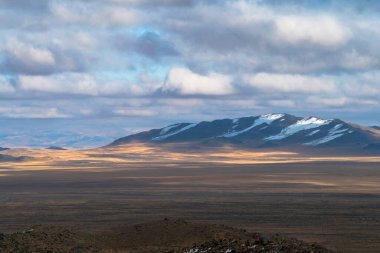 Sarı bozkır ve gün batımında karanlık dağlar. Bulutlu mavi gökyüzü. Atmosferin dinginliği. Kosh-Agach, Altai, Rusya yakınlarındaki sonbahar manzaraları