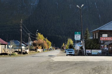 Aktash, Rusya - 28 Eylül 2023: Otoyol boyunca yüksek dağların arka planındaki Altai dağ köyü. Caddelerin kesiştiği yer, eczane. Döviz borsası tabelası. Altai Cumhuriyeti.