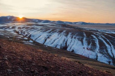 Altai Cumhuriyeti 'ndeki Kokorya arazisindeki sonbahar karlı dağların üzerinde inanılmaz bir gün batımı. Gezgin bir şehvet. Sibirya 'nın dağ buzulları ve Altai arka planının güneşli gökyüzü..
