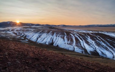 Gün batımı manzaralı dağ katmanları vadideki altın bulutlarla bulutlu gökyüzünün altındaki dağ siluetleri arasında. Canlı panoramik gün batımı ya da aydınlık renkteki dağ vadisinde gün doğumu manzarası.