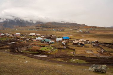 Sonbaharın sonlarında dağın altındaki küçük Sibirya köyünün hava manzarası. Rusya 'nın Belyashi köyünde, yağmurlu sabahların altın sonbahar manzarası, Altai Krai.