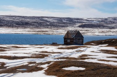 Kışın bir dağ gölünün kıyısında bitmemiş ahşap bir ev. Karlı pas. Altai 'nin uzak bir bölgesi.