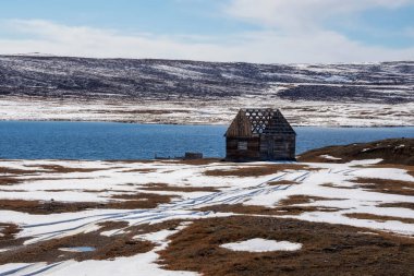 Kışın bir dağ gölünün kıyısında bitmemiş ahşap bir ev. Karlı pas. Altai 'nin uzak bir bölgesi.