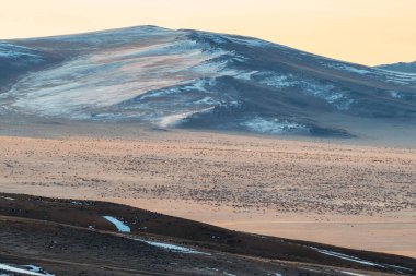Yumuşak, sonbahar, dağ bozkırları. Güneş ışığında geçitten dağ vadisine müthiş bir dağ manzarası ve büyük kar dağları siluetleri. Dağ otlağı. Sert yüksek irtifa manzarası.