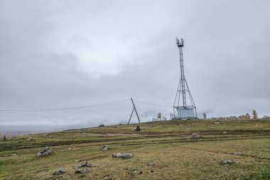 Autumn Hill 'deki baz istasyonu. Yüksek çelik hücre kulesi dağın tepesinde, kasvetli gökyüzünün altında, kalın gri bulutlar altında..