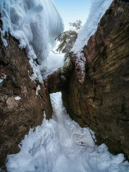 Narrow path through snow drifts between rocks, a stone vault, a cave. Beautiful bizarre rocks in the famous place \