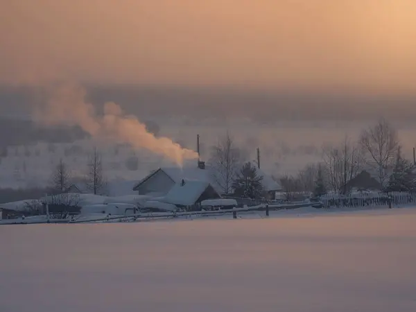 Soft focus. Sunrise village in the winter season. frozen trees and houses. Traditional village houses in winter in sunny morning frosty weather. Old northern residential architecture of Russia.