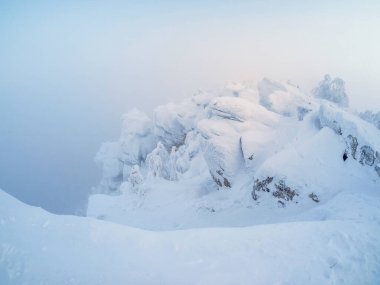 Yumuşak odaklanma. Donmuş sisli güzel karlı ve kayalık dağ manzarası. İlahi kış minimalist manzarası.