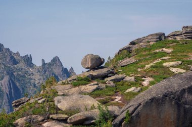 Büyük dengeleyici taş, doğal bir fenomen. Uçurumun kenarına büyük bir kaya düştü. Gün ortası manzarası, Batı Sayan. 