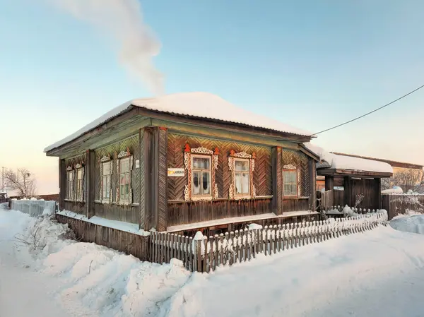 Winter in the Russian countryside. Ancient wooden hut under the snow. Rural life and way of life preserved to the present day. Winter street in the village of Cherdyn, Perm region. Russia.