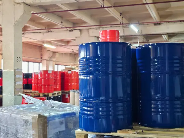 Metal blue and red barrel in the warehouse, 200-liter chemical barrels are arranged on wooden pallets and waiting for delivery. Petroleum industry, and chemical industry concepts.