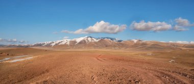 Dağlardan geçen yol. Dağ yolunda geziniyorum. Parlak panoramik minimalist alp manzarası yaylalardaki otlar arasında taşlı patikalar. Yokuş yukarı bir yol. Dağın eteklerinde.
