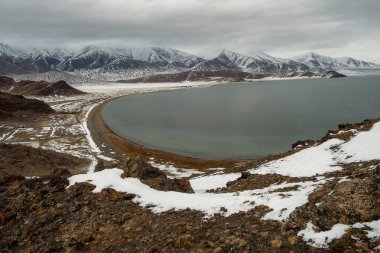 Büyük oval dağ gölünün panoramik manzarası. Bulutlu bir sabahta Tolbo Nur Gölü. Tolbo-Nuur Gölü yakınlarındaki Moğol doğal manzaraları kuzey Moğolistan 'da dağlar ve kayalarla çevrilidir..