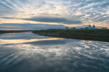 Sabah manzarası, nehirde gün doğumu. Geniş nehir, ufuk, bulutlar suya yansıyor. Dunilovo köyünün manzarası. Duyuru Manastırı, Ivanovo bölgesi, Rusya. Rusya 'nın Altın Yüzüğü