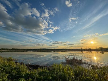 Akşam manzarası, nehirde gün batımı. Geniş nehir, ufuk, bulutlar suya yansıyor..
