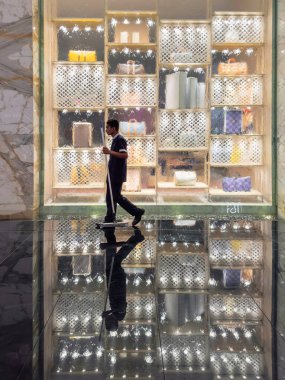 Dubai, BAE - 27 Mayıs 2024: Butik perakende satış. Süpürgeyle gezen temizlikçi, butik pencerenin önünden geçer. Atlantis 'in mimarisi, Dubai Kraliyet Oteli iç mimarisi. Dikey görünüm.