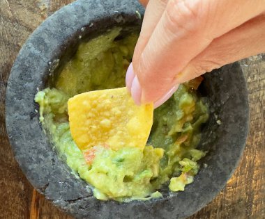 Guacamole soslu cips. Tortilla soslu kadın eli ya da lezzetli guacamole soslu nachos.