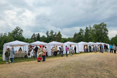 Gatchina, Rusya-Haziran, 08-2024: Küçük bir kasaba olan Gatchina fuarı başlıyor. İlk alıcıları görüyoruz. Tepedeki beyaz çadırlarda..