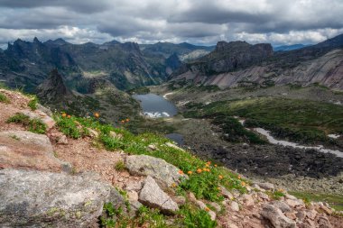 Dağın yamaçlarındaki kayalıkları işaret etti. Hayalet kayalar. Güneşli bir sabahta büyük çatlamış sivri uçlu taşlarla muhteşem manzaralı bir yaz manzarası. Keskin kayalar ve buzul gölü. Ergaki Parkı, Batı Sayans.