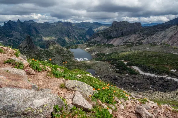 Dağın yamaçlarındaki kayalıkları işaret etti. Hayalet kayalar. Güneşli bir sabahta büyük çatlamış sivri uçlu taşlarla muhteşem manzaralı bir yaz manzarası. Keskin kayalar ve buzul gölü. Ergaki Parkı, Batı Sayans.