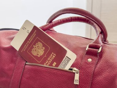 Kırmızı pasaport ve biniş kartı çantanın cebinden çıkıyor. Kırmızı Rus pasaportlu, turistik kırmızı çantalı bir uçak bileti. Turizm ve seyahat kavramı.