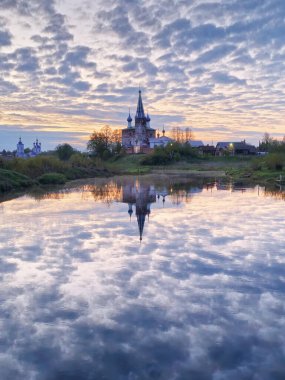 Dunilovo köyünün manzarası. Duyuru Manastırı, İvanovo Bölgesi, Geniş Nehir, Ufuk, Bulutlar suya yansıyor. Sabah manzarası, nehirde gün doğumu.