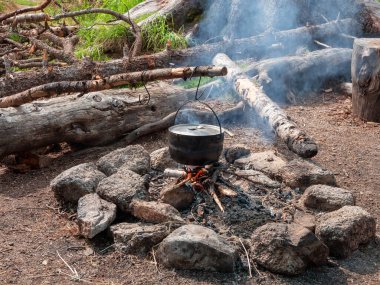 Kamp mutfağı. Vahşi doğada yemek pişirmek. Ateşte kurumuş çaydanlık var. Vahşi doğada hayatta kalmak. Calderon 'lu harika bir alev. Esrar kamp ateşinde sallanıyor..