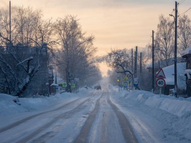Kış Alacakaranlık Yolu. Gün batımında karlı kışta karlı ve sisli bir yolda kar yağışı var. Kış yolunda yükselir ve alçalır. Buz gibi kırsal alan. Cherdyn şehrinde sert kış