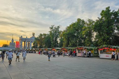 Moskova, Rusya - 12 Temmuz 2024: VDNKH akşam Moskova 'dadır. Rusya Fuarı 'nın Tadı. Turistler ve Moskovalılar yürüyüşe çıktı. Canlı bir insan akışına sahip bir kare. Mallı tepsiler.