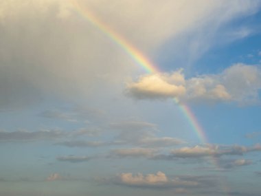 Beautiful rainbow in the sky over clouds. Dramatic sky after the rain. Meteorology, heaven, hope, peace concept, copy space. clipart