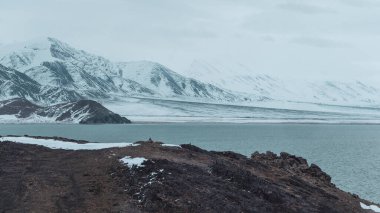 Bulutlu bir sabahta Tolbo Nur Gölü. Kuzey Moğolistan 'da dağlarla ve kayalarla çevrili Tolbo-Nuur Gölü yakınlarındaki Moğol doğal manzaraları. Panoramik görünüm.