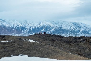 Kar dağlarının tepesindeki turistler. Moğolistan yolculuğu. Sabah dağı manzarası.
