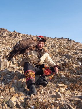 Ulgiy, Moğolistan - 30 Eylül 2023: Altın kartal avlayan çok yaşlı bir erkek avcının portresi. Yaşlı göçebe ve avcı kuş. Dikey görünüm.