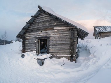 Bir kulübe, bir kulübe, kışın köyün kıyısında terk edilmiş bir ev. Kar yığınlarının arasından eve giden yol. Perma Bölgesi. Rusya