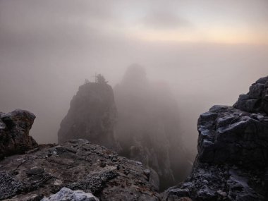 Hayalet dağlar, yoğun sisteki kayalar. Yüksek dağları olan doğal bir arka plan, dik bir dağ yamacı. Bulutlu gökyüzündeki büyük uçuruma hayalet atmosferik bir bakış..