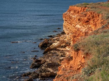 Gün batımında güneşli plaj Sivastopol 'da Cape Chersonesos. Karadeniz, sarp kıyılar, ufalanan kayalar.