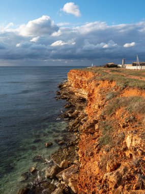 Gün batımında güneşli plaj Sivastopol 'da Cape Chersonesos. Karadeniz, dik kıyılar, ufalanan kayalar. Dikey görünüm.