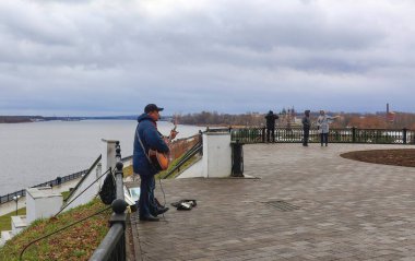 Yaroslavl, Rusya - 19 Kasım 2024: Bir sokak müzisyeni gitar çalar ve şarkı söyler. Yağmurlu bir sonbahar gününde yaroslavl seti. 